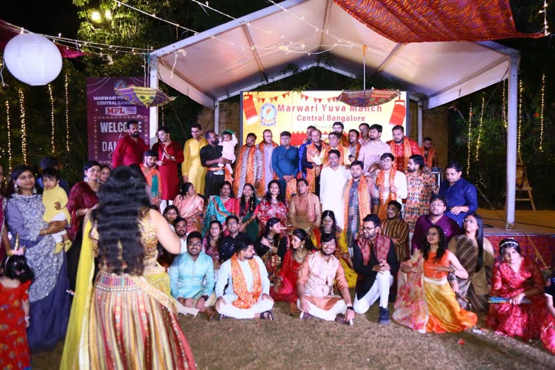 Around fifty people in traditional dress grouped on stage under the Marwari Yuva Manch Central Bangalore banner.